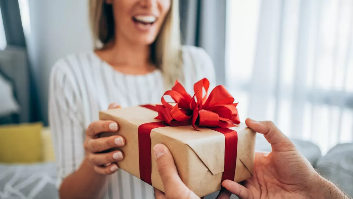 cheerful young woman receiving a gift from her boyfriend